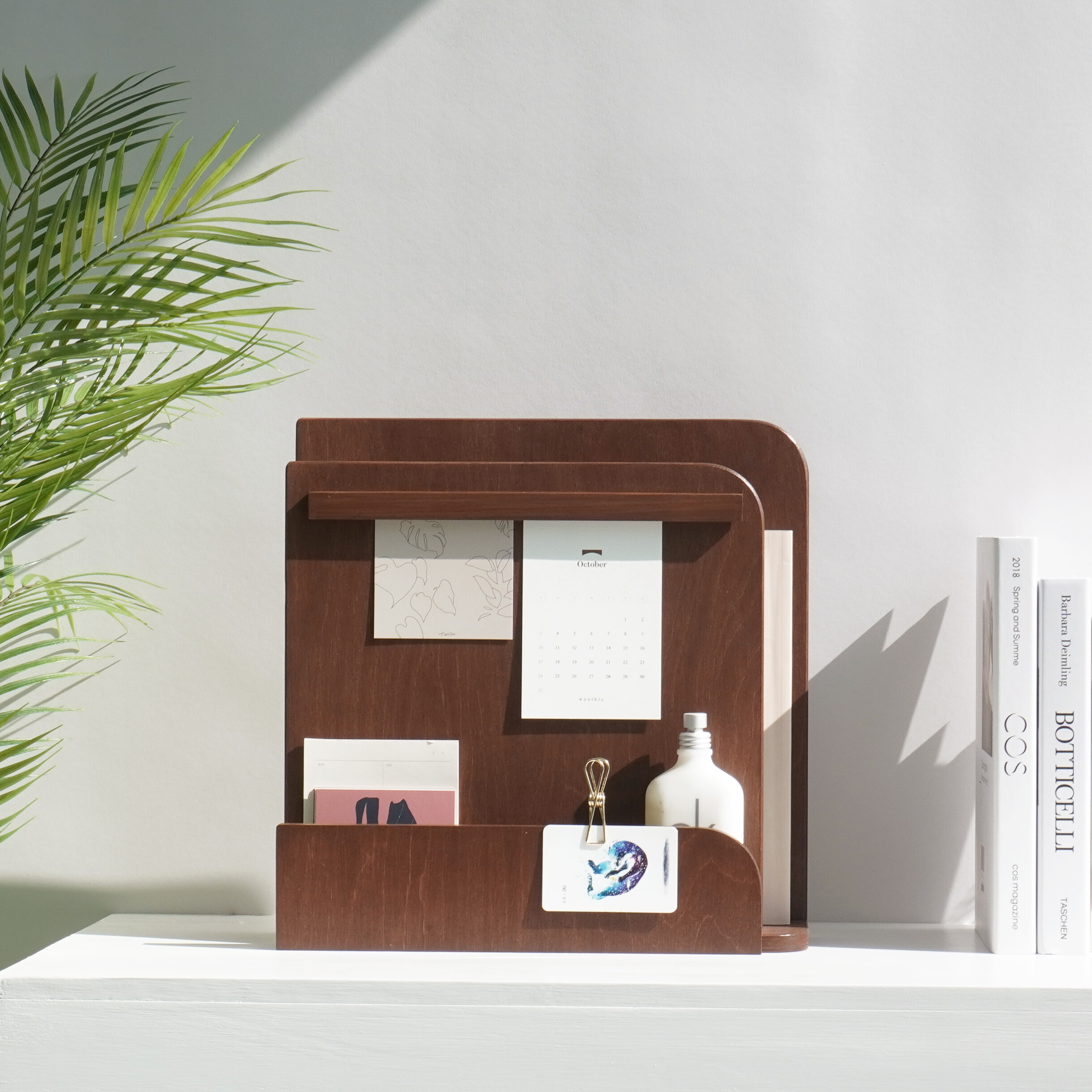 흰 벽 바탕에 짙은 우드톤 메모 오거나이저가 놓여 있는 모습