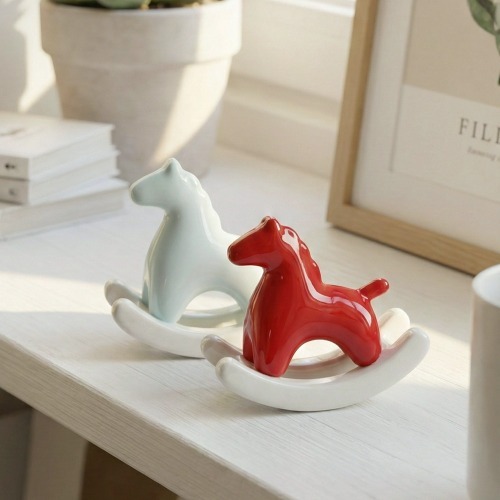 테이블 위에 흔들 목마 모양의 흰색, 빨간색 오브제가 놓여 있는 모습