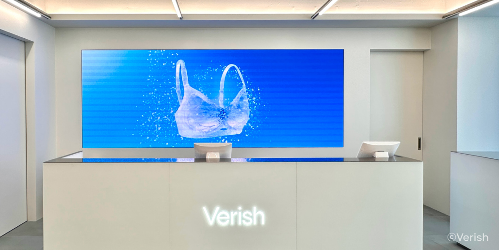 베리시 플래그십 스토어의 모습이에요. 전체적으로 흰 인테리어인데, 흰색 계산대 뒤 벽에 달린 전광판에서 이미지가 송출되는 중이에요. 이미지는 하늘색 바탕에 얼음 재질 브래지어 그래픽이에요.