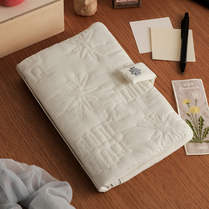 나무색 바탕에 흰색 책책 손가방이 놓인 모습. 