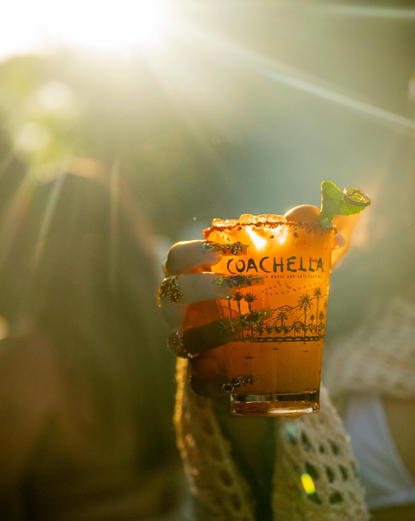 컵을 들고 있는 손에 'Coachella'라고 적혀 있어요.