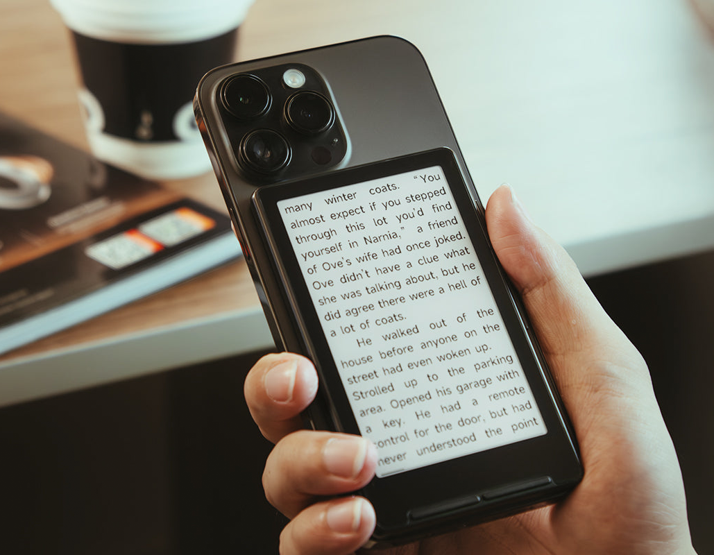 사람의 손이 핸드폰을 들고 있는 모습. 핸드폰 뒷면에는 x4 제품이 붙어있고, 제품 화면에는 텍스트가 띄워진 모습.