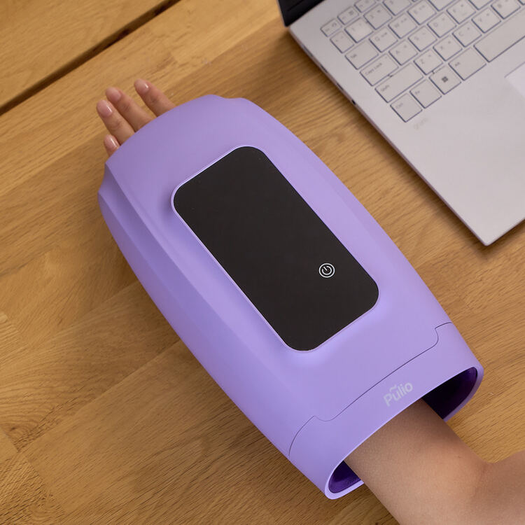 테이블 위에 보라색 기기가 놓여 있고, 기기 안에 손을 넣고 있는 모습.