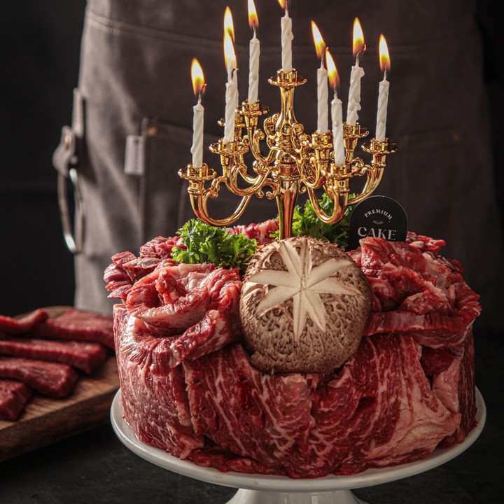 붉은색 고기로 케이크를 만든 모습. 케이크 중앙에 초가 꽂혀 있음.