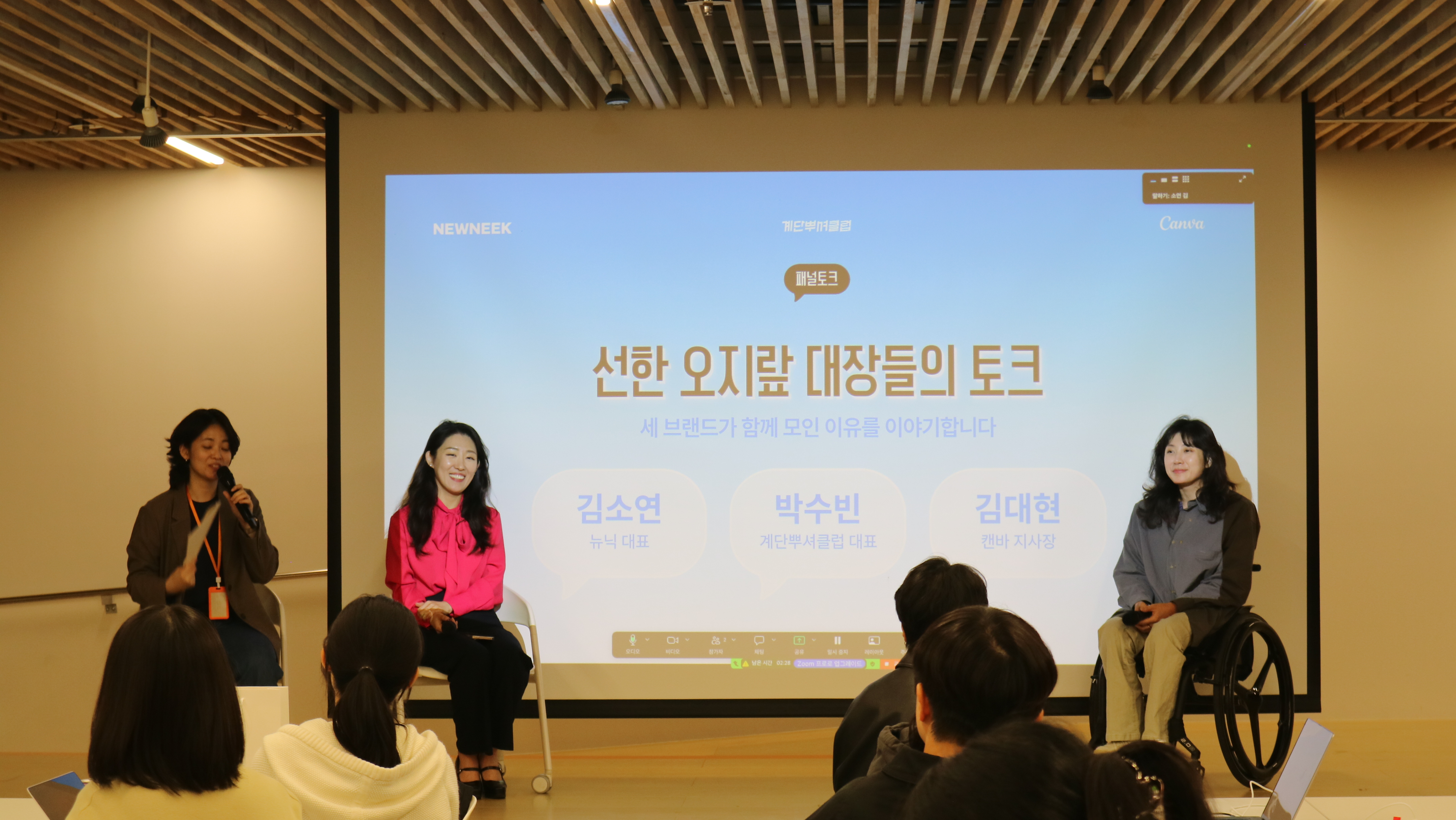 실내 행사장 무대 위에서 세 명의 발표자가 패널 토크를 진행하고 있어요.